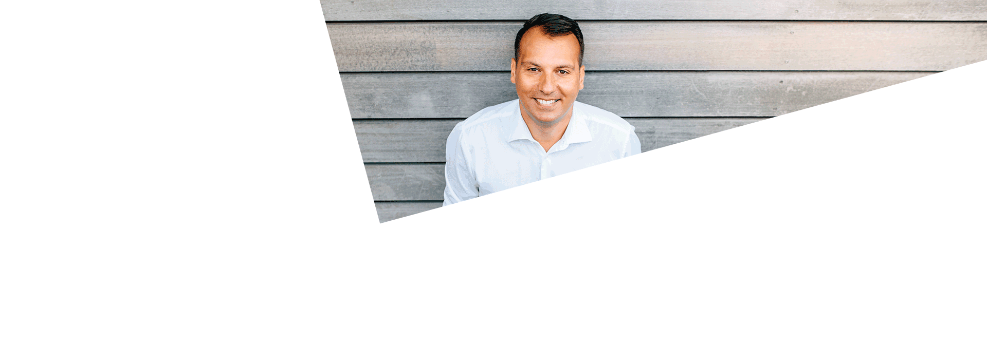 Dr. Giannakos, Gründer von OMOCURA und Schulterspezialist, Porträt vor moderner Holzfassade