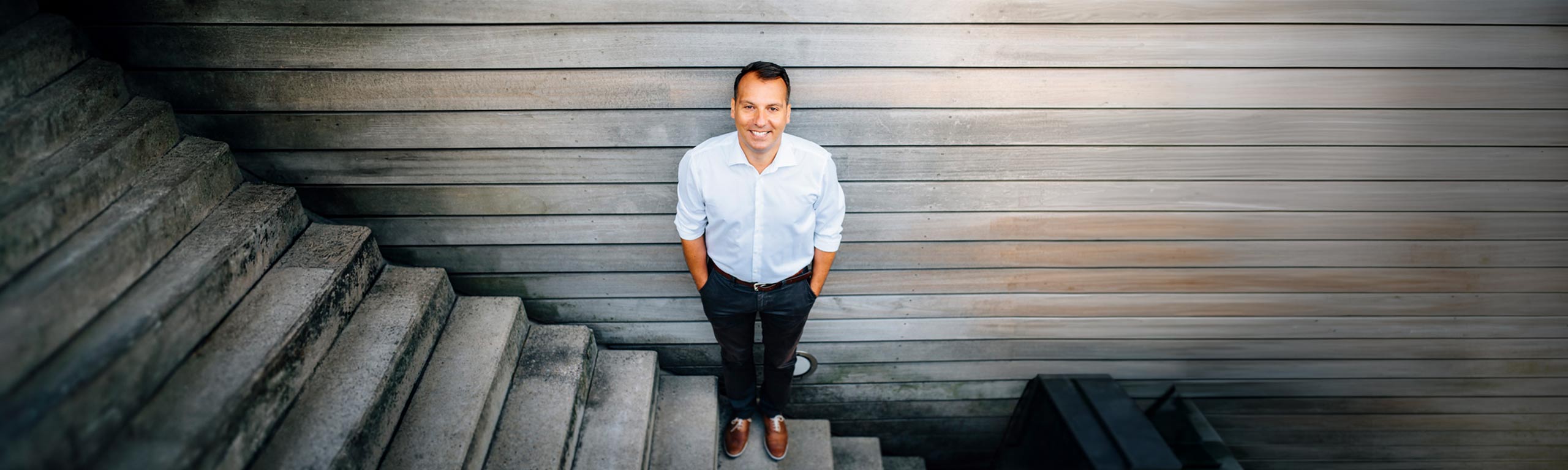 Dr. Antonios Giannakos, Gründer der OMOCURA Praxis, steht auf einer Treppe und blickt in die Kamera.